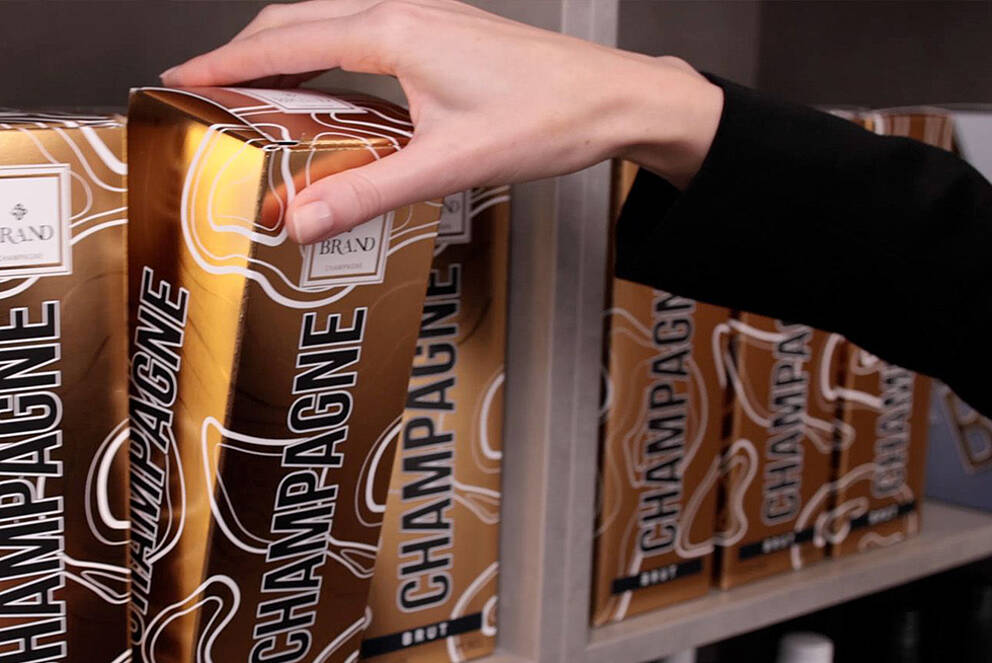 Enhancing Attractiveness & Creativity in Secondary Packaging and Outer Packaging Champagne packaging with cold foil, being taken from a shelf